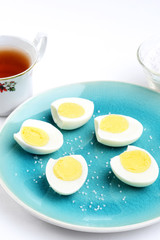 sliced boiled eggs on a blue plate with salt