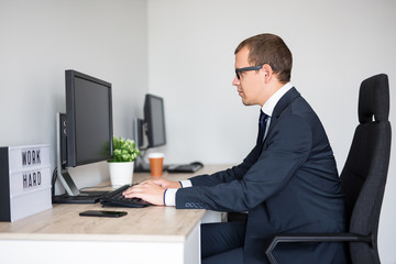 side view of young handsome business man using computer in modern office
