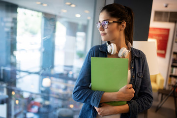 Beautiful happy student woman studying in library