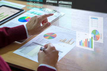 Businessman interacts with virtual reality graphics while deeply reviewing a financial report for a...