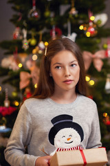 Beautiful girl with present over Christmas tree