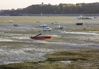 Boats on dry land at the beach at low tide in Cancale famous oysters production town, Brittany, France,