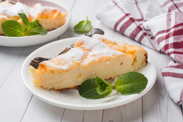 Cottage cheese casserole on a plate with powdered sugar and mint leaves. Selective focus