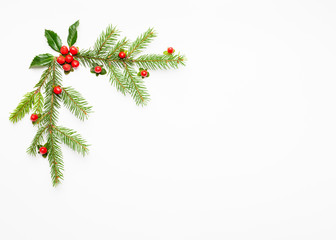 Christmas composition  with branches of spruce and holly with red berries on white background. Merry christmas greeting card with empty space for holiday text.