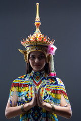The beautiful woman wearing Thai southern folk dancing costume,made from colorful bead,and the headress on her head,press hands together at the chest,showing performance of culture