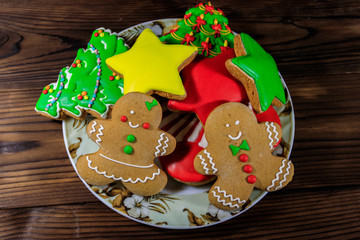 Plate with tasty festive Christmas gingerbread cookies on wooden table. Top view