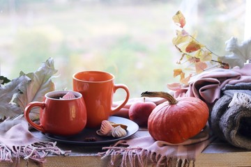 Two cups of coffee, meringues, pumpkins, apples, leaves, plaid on the background of the window, home comfort concept, Thanksgiving, autumn season