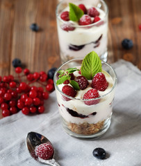 Healthy breakfast - yogurt with fresh berries and muesli served in glass jar, on wooden background