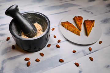 Crush almonds with a mortar and pestle. Brownie with almonds cooking on white wooden background. Preparation of nut flour for baking
