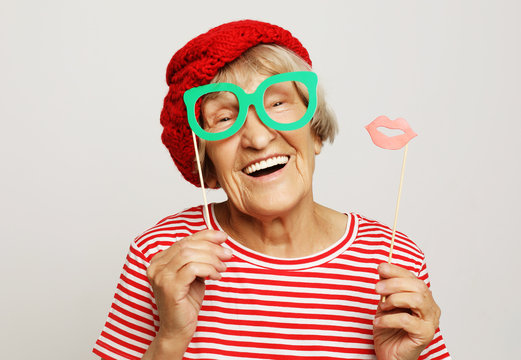 funny grandmother wearing red clothes holding falce glasses and ready for party