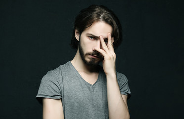 unhappy man touching his forehead over black background