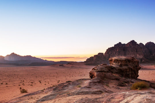 View of the sunset over the Wadi Rum desert in Jordan, with mountains in the background and blue yellow brown and red colors. Feeling of peace and tranquility. © Enrico Tricoli