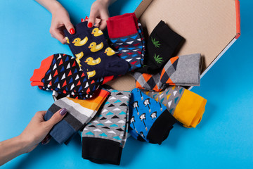 multi-colored socks in the form of a circle folded into a box, several female hands touch socks,...