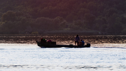 Sunset on the river with silhouette of the small fishing boat