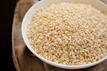 Organic Arborio rice in a white bowl, low angle view. Close-up.