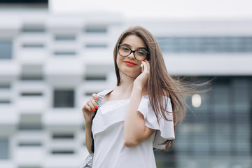 Smiling businesswoman using her mobile phone. Cheerful attractive young businesswoman in glasses standing and using mobile phone