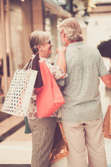 A senior couple enjoying shopping in the mall. Happiness and relax with a lot of bags. Both smile and hug each other. White and gray hair.