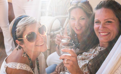 A group of females people in friendship enjoying a party on the terrace toasting with red wine. Beautiful women. Simplicity and happiness together