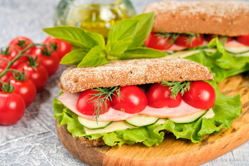 Sandwich with cheese, cucumber and Cherry Tomato on a wooden board. The sandwich is decorated with a lettuce leaf and cherry tomatoes.