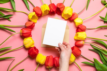 Composition of fresh flowers, a bouquet of red tulips, paper texture background with envelope. International Women's Day, mother's day greeting concept.