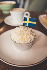 Swedish cupcake with national flag on a wooden table in a cafe.