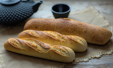  Homemade bread, two baguettes and chiobata lie on a table of natural wood and a linen napkin.