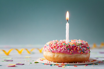 Sweet donut and one burning candle. Happy birthday concept.