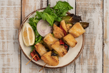 Skewed sole fish served with salad on table