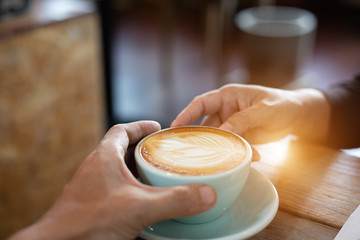 Hand Women and man put a Latte arts coffe hot coffee on wooden table.barista love art concept.
