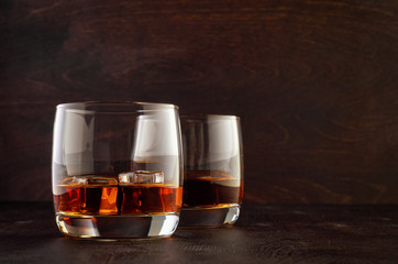Two glasses of whiskey with ice on the wooden table