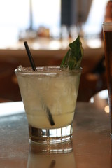 cocktail on table with straw and basil leaf