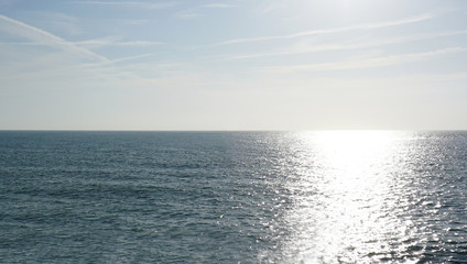 Empty sea to the horizon, daytime. Visible light path on the water.