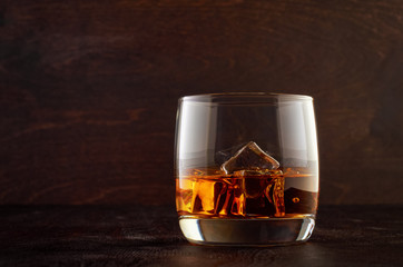 A glass of whiskey with ice on a wooden table