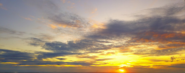 Beautiful Sunset in the sky with sky blue and orange light of the sun through the dark clouds in the sky, Orange and red dramatic colors - Image