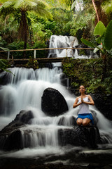 Healthy life. Yoga retreat. Young woman sitting on the rock, meditating, practicing yoga, pranayama...