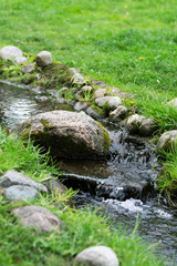 Fototapeta na wymiar Stream of water or small waterfall with moss on the rocks