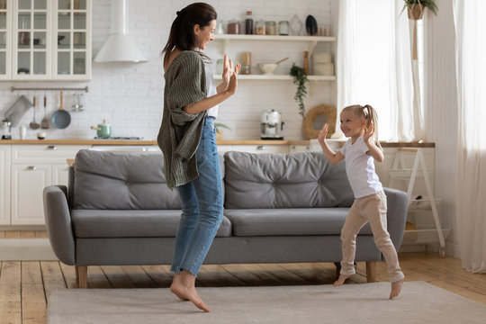 Full-length image mother dancing with preschool daughter at home