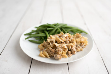 Turkey Stroganoff on white wood table with green beans and seasonings