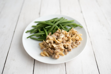 Turkey Stroganoff on white wood table with green beans and seasonings