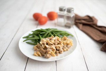Turkey Stroganoff on white wood table with green beans and seasonings