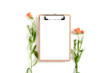 Clipboard mockup with calendula flowers on white desk