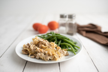 Turkey Stroganoff on white wood table with green beans and seasonings