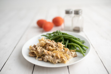 Turkey Stroganoff on white wood table with green beans and seasonings