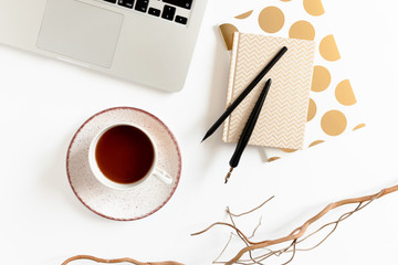 White desk with laptop, golden notepads, glasses, mug of coffee, corilus branch and stationery