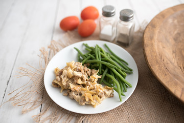 Turkey Stroganoff on white wood table with green beans and seasonings