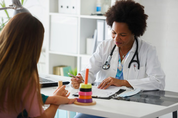 Obraz premium Female doctor pediatrician with baby patient and mother. Pediatrician doing an infant medical exam. Early child development and care