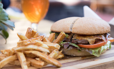 Delicious hamburger served with vegetables, french fries and a cold glass of beer