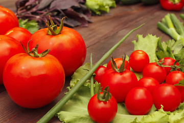 Fototapeta na wymiar Fresh summer tomatoes and greens on a wooden table