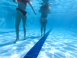 Underwater view from two girls in bikini standing in a pool