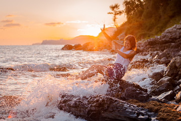 One young beautiful girl splashes and splashes the sea at sunset. Summer landscape sea, Islands and...